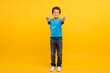 Boy in blue t-shirt giving thumbs up on sunny yellow background