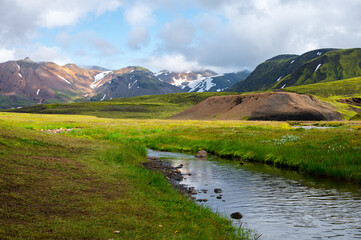 Amazing Icelandic landscape with snowy mountains, river and field on a sunny day at famous Laugavegur hiking trail. Iceland