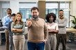 © Mediteraneo - Boss standing in front of his colleagues in the office with thumbs up