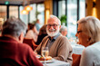Elderly man smiling while enjoying an elegant dinner with friends at a restaurant.