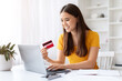 © Prostock-studio - Smiling Asian Woman Using Laptop And Credit Card In Home Office