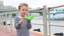 The Boy Stands On The Embankment And Points A Finger At Snout Of Ship