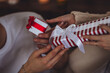 Happy loving young beautiful couple exchanging gift boxes for Christmas, new year or saint Valentine's Day. Man and woman in casual clothes holding presents, smiling, enjoying holidays at home