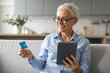 © Prostock-studio - senior woman shopping using digital tablet and credit card indoors