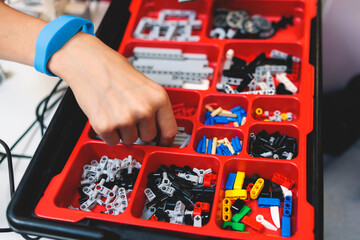 Group of diverse children kids with robotic vehicle model, close-up view on hands, science and engineering lesson in a classroom, making, coding and programming a robot in a school, robotics projects