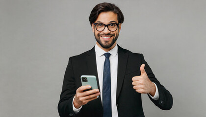 Wall Mural - Adult fun successful employee business man corporate lawyer wear classic formal black suit shirt tie work in office hold use mobile cell phone show thumb up isolated on plain grey background studio.