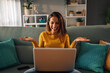 © Zamrznuti tonovi - Happy caucasian woman using laptop while spreading her hands and smiling