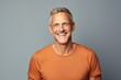 © Igor - Portrait of happy mature man in orange t-shirt over grey background.