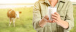 © Pixel-Shot - Woman holding glass of milk in pasture with grazing cow