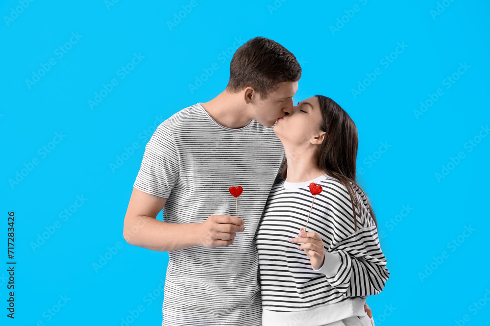 Happy young couple with hearts kissing on blue background