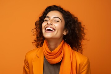 Happy young woman with closed eyes and orange scarf over orange background.