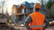 © sirisakboakaew - construction engineer standing with his back and watches at a house building construction.