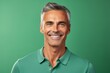 © Igor - Handsome middle-aged man smiling and looking at camera against green background
