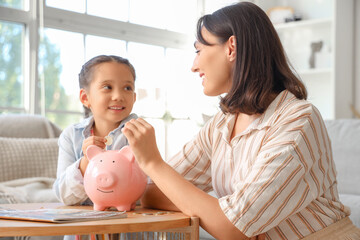 Sticker - Little girl with her mother putting coins into piggy bank at home