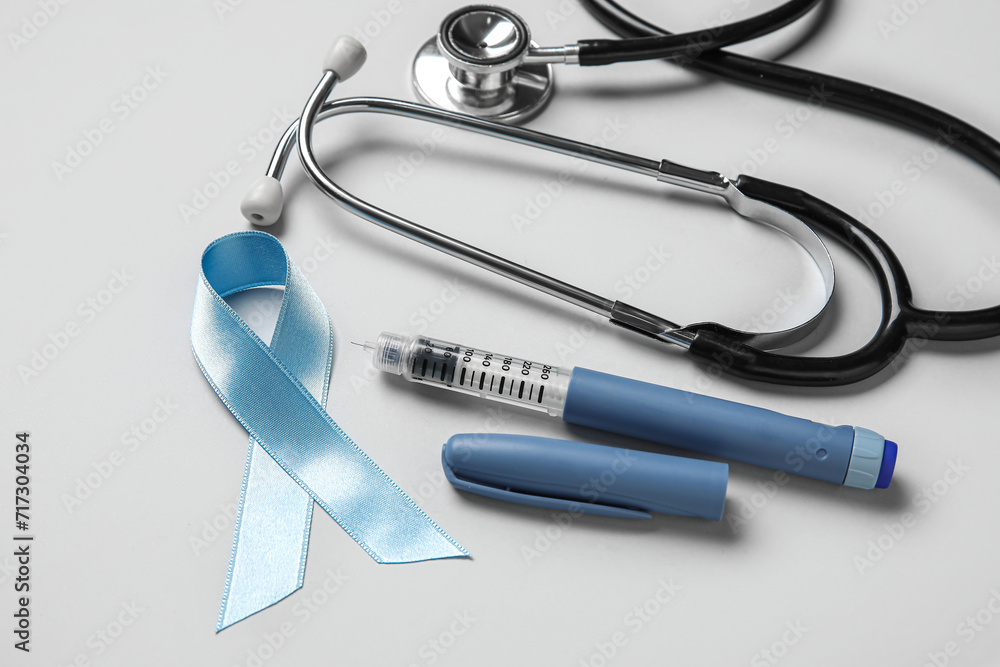 Awareness ribbon with lancet pen and stethoscope on light background. Diabetes concept