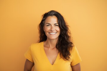 Wall Mural - Portrait of a smiling woman looking at camera isolated over yellow background