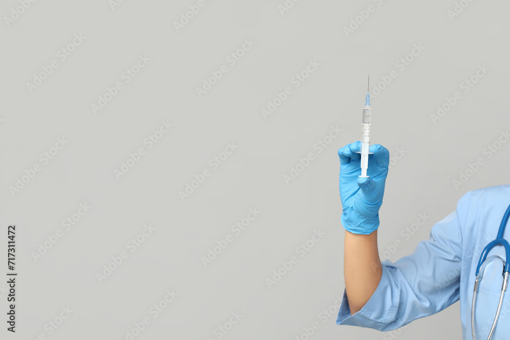 Female doctor hand with syringe on grey background