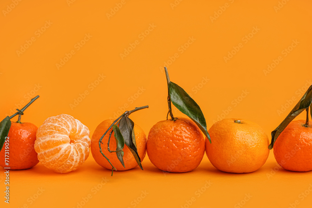Tasty tangerines with leaves on orange background