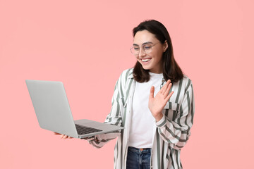 Canvas Print - Pretty young woman with laptop waving hand on pink background