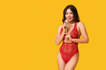 Poster - Beautiful young happy Asian woman in sexy lingerie with tulip flower on yellow background. International Women's Day