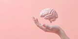Fototapeta Natura - hand holding a 3D brain over a pink background