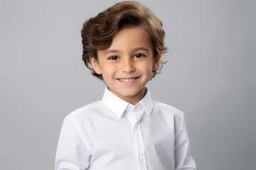 Portrait of a cute little boy in a white shirt on a gray background