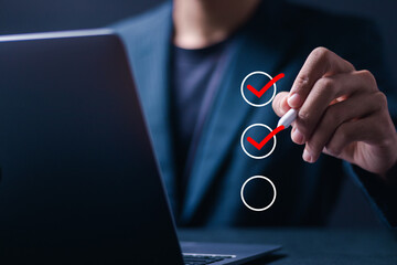 Wall Mural - Checklist concept. Businessman use pen Checking mark on checkboxes for business performance monitoring and evaluation.
