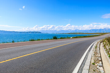 Wall Mural - Asphalt highway road and blue lake with mountain nature landscape under blue sky