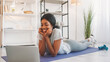 © golubovy - Online fitness. Video communication. Young sporty woman talking at laptop internet virtual chat meeting on yoga mat after exercising in home living room.