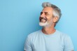 © Iigo - Portrait of a happy senior man with grey hair and beard on blue background