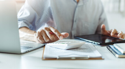 Wall Mural - Close-up shot, businessmen or accountant using calculator calculate expenses and budget to planning and start new business and use a tablet to check orders from customers