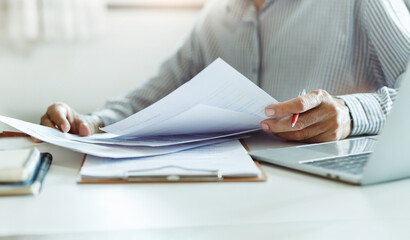 Wall Mural - Asian businessman reviewing document reports at office workplace with computer laptop. legal expert, professional lawyer reading and checking financial documents or insurance contract