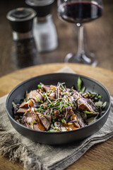 Wall Mural - Roast beef salad with herbs and balsamic sauce in the style of a bowl on a restaurant table