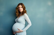 Portrait von einer schwangeren Frau in einem hellblauen Kleid vor einer Blauen Wand, Platz für Text auf der rechten Seite 