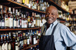 © PixelGallery - Portrait of smiling mature african american bartender standing at counter in bar