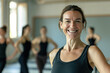 © PixelGallery - Portrait of smiling mature woman standing with arms crossed in fitness studio
