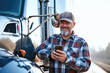 Smiling mature man using mobile phone while standing near his semi truck