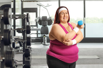 Canvas Print - Plus size female exercising at a gym and holding her elbow