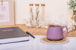 Morning brew in a stylish purple cup with a golden spoon, set on a pristine white desk adorned with boho-inspired decorations. Perfect for coffee shop banners or cozy home decor.