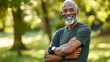 © Studio Nova - mature man with a grey beard is smiling and standing with his arms crossed, wearing a fitness tracker, in a park setting