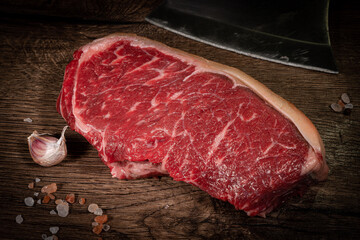 Poster - Fresh raw piece of beef meat, striploin steak on a black background, top view. Marbled piece of meat New York