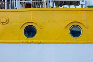 Two porthole windows on old passenger travel vessel.