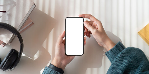 Wall Mural - Top view mockup image of a woman holding mobile phone with blank white screen while sitting