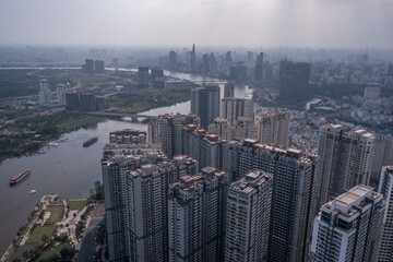 Wall Mural - Saigon river with container barges, city skyline, high rise buildings aerial photo with dramatic sky.