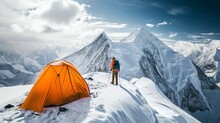 Mountaineer Next To A Striking Orange Tent On A Snowy Peak.