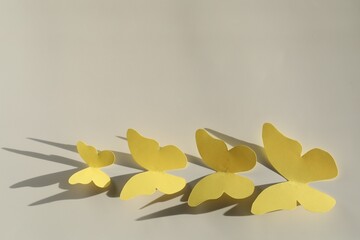 Wall Mural - Yellow paper butterflies on light grey background, top view. Space for text