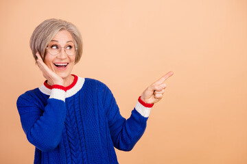 Sticker - Photo of impressed woman dressed knitwear warm sweater look empty space promo palm on cheekbone isolated on beige color background