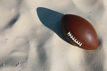 Wall Mural - American football ball on sand, above view. Space for text