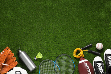 Different sports equipment on green grass, flat lay. Space for text