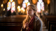 young woman praying in church with blurred background - faith and religion concept